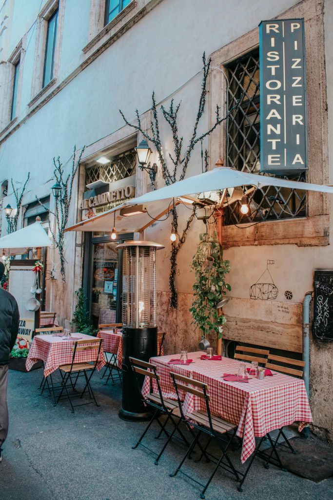 Cozy Italian cafe with outdoor seating in Rome, featuring red checkered tables.