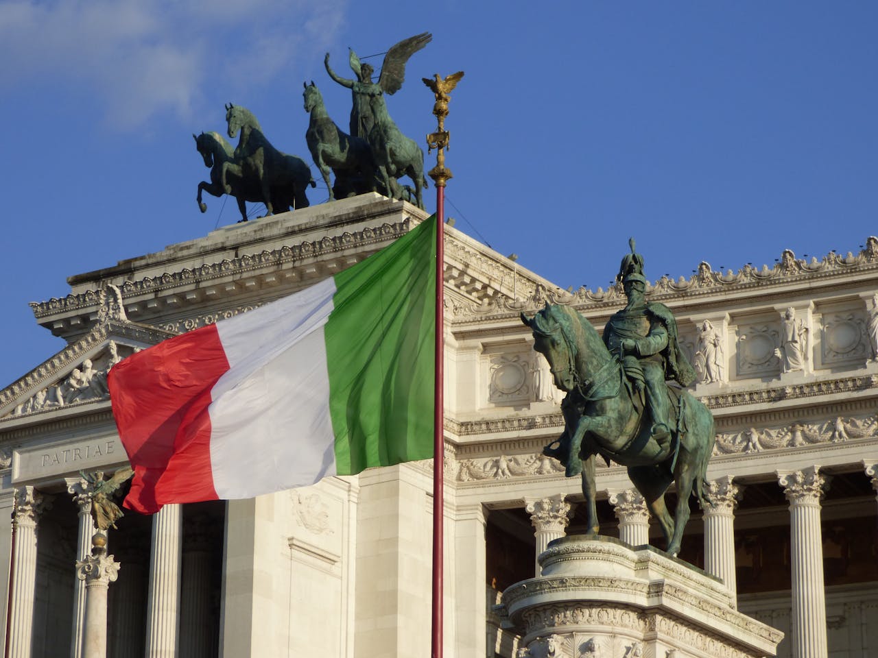 Italian flag waving at the Altare della Patria, showcasing Roman architecture and historical monuments.